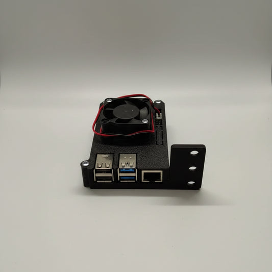 A black 3D-printed electronic enclosure with two USB 3.0 ports, an RJ45 Ethernet port, and a small black cooling fan with red wires on top, shown on a light surface.