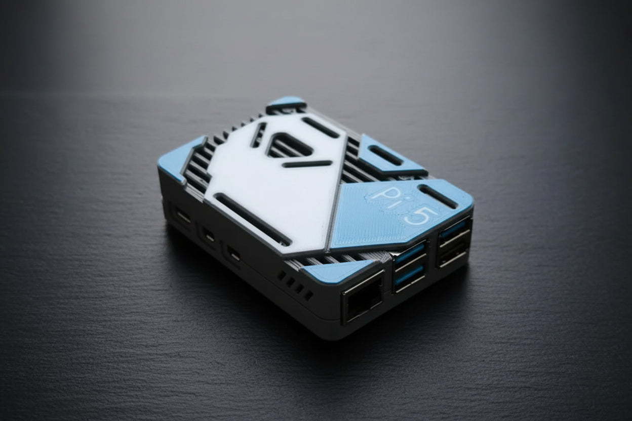 A 3D-printed custom enclosure for a Raspberry Pi 5, featuring a white and blue geometric design with ventilation slots and USB ports, resting on a textured stone surface.
